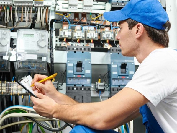 A licensed electrician in Brisbane testing a household electrical switchboard for safety.